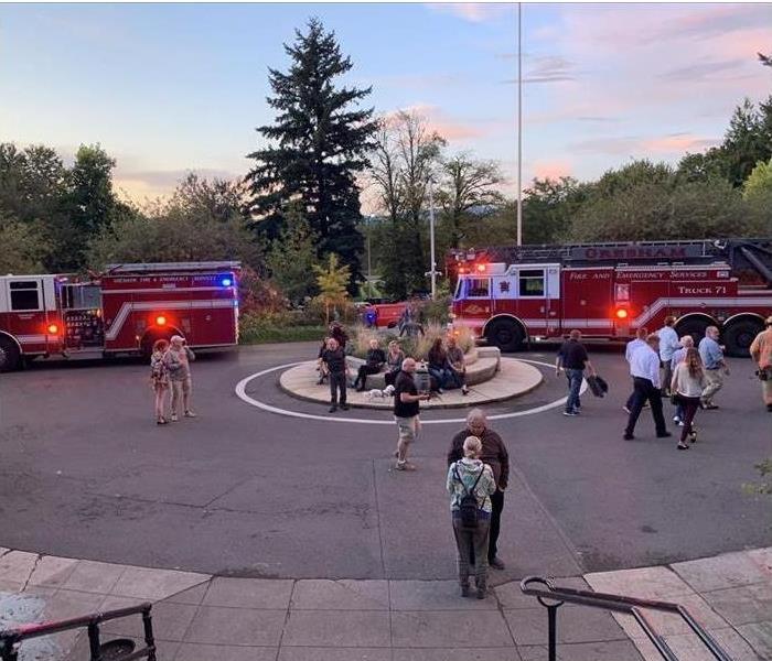Hotel guests and firefighters outside of burning hotel